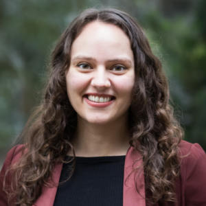Photo of Chandani smiling in front of a blurry outdoor background.