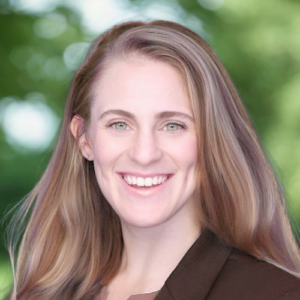 Photo of Melissa smiling in front of a blurry outdoor background.